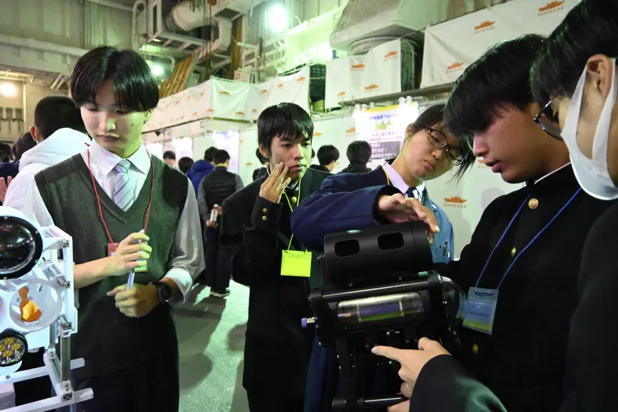 白いフレームのTriton機体を囲んで来場者と話す様子